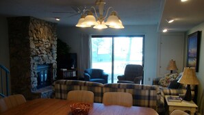 A dining area with a wooden table, chairs, and a stone wall. - 2King Master Suites, Walk to golf, Outside heated pool (Cedar)