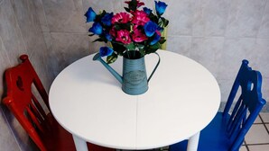 A round white table with a blue watering can holding a bouquet of flowers. - Casa a Boleriña 1 (Poio)
