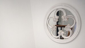 A staircase with white walls, a wooden handrail, and a decorative mirror with ornate designs. - Casa a Boleriña 1 (Poio)