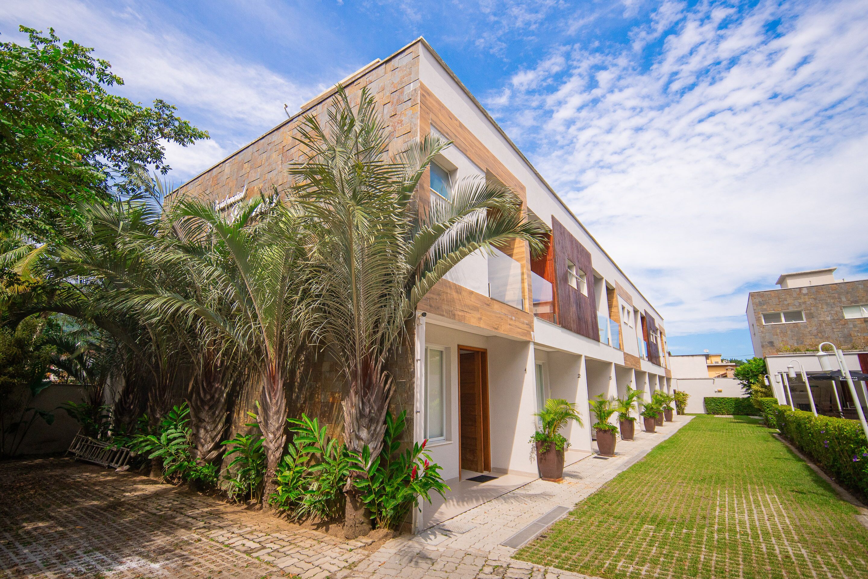 A modern multi-story building with a brick facade, a covered entrance, and a well-maintained lawn.