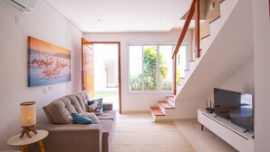 A modern living room with a sofa, TV, and artwork. - Residencial Las Salinas (São Sebastião)