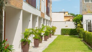 A modern building with a row of potted plants along a paved walkway. - Residencial Las Salinas (São Sebastião)