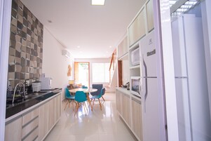 Een moderne keuken met een eethoek, met een keukeneiland, stoelen en een koelkast.