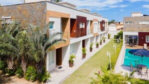 A modern hotel with a pool, outdoor seating, and a well-maintained garden. - Residencial Las Salinas (São Sebastião)