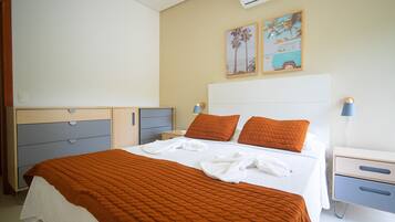 A hotel room with a large bed, two pillows, a bedside table with a lamp, and a nightstand.