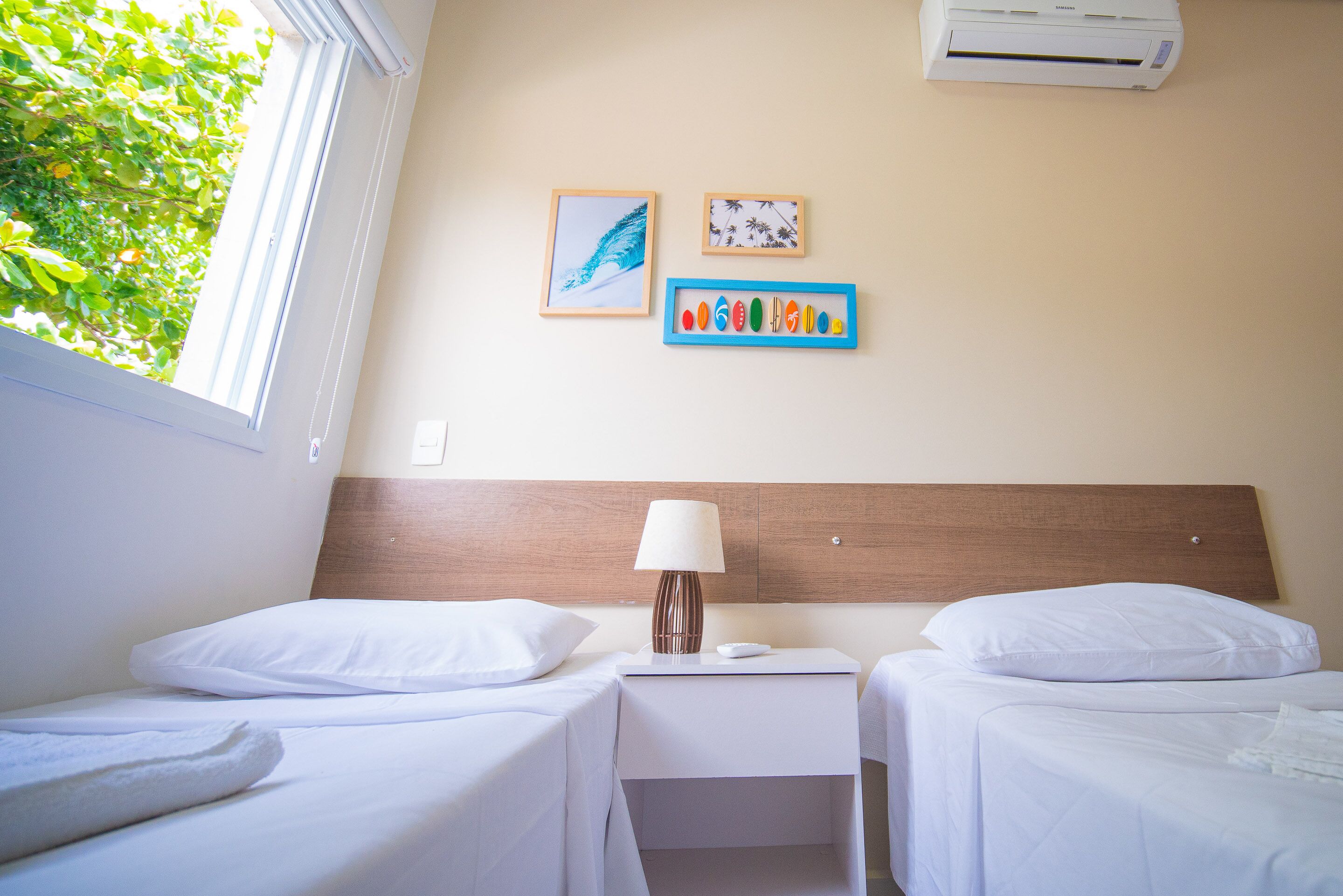 Habitación de hotel con dos camas, una mesita de noche con lámpara y decoración en la pared.