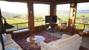 Un salón acogedor con un ventanal grande, un televisor de pantalla plana y un mobiliario cómodo.