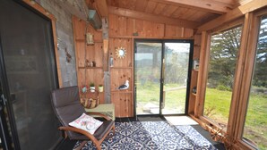 Un interior de madera con una mecedora, un tapete estampado y vistas al exterior.