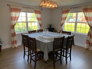Une salle à manger avec une table ronde, six chaises et un lustre.