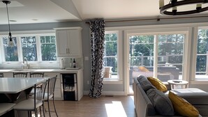 A modern kitchen with a central island, dining area with chairs, and a grey sofa with cushions. - Waterview 5 bedroom home.  Sleeps 10 (Cornwall)