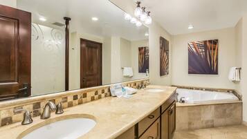 A bathroom with two sinks, a bathtub, and a large mirror.