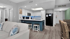 Une cuisine moderne avec des meubles blancs, un îlot central doté de tabourets et un four à micro-ondes.