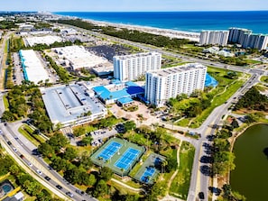 An aerial view of a coastal city with a large hotel complex, multiple high-rise buildings, and a beach in the background.
