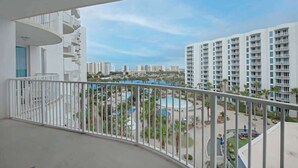 Un balcon donnant sur un complexe hôtelier, avec vue sur une piscine et plusieurs bâtiments.