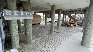 En træterrasse med et skilt, der står "BEACH", og en træfad.