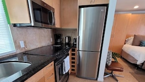 Eine kompakte Küche mit Edelstahl-Kühlschrank, Mikrowelle und Kaffeemaschine.
