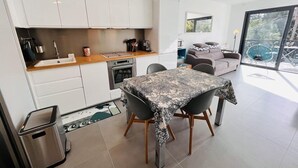 Una cocina moderna con armarios blancos, una encimera de madera y un comedor con mantel estampado.
