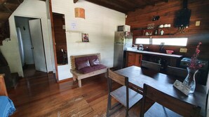 A rustic kitchen with wooden cabinets, a refrigerator, and a dining area with a wooden table and chairs. - PEACE AND NATURE AT ITS BEST BEACH, HERE IN URUGUAY (La Pedrera)
