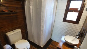 A bathroom with a wooden floor, a white toilet, a shower with a white curtain, and a wooden vanity with a sink. - PEACE AND NATURE AT ITS BEST BEACH, HERE IN URUGUAY (La Pedrera)