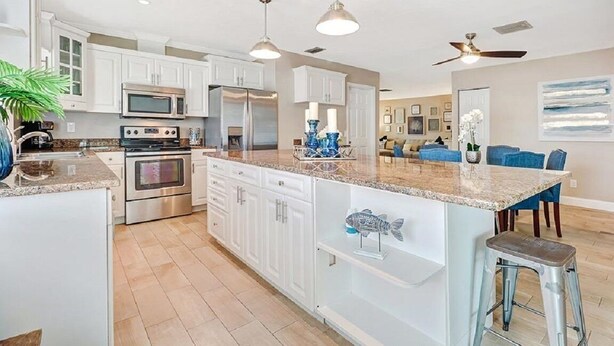 A spacious kitchen with white cabinets, stainless steel appliances, and a granite countertop. - -Sea Coast Living At it's BEST, Heated pool, near beaches, shops, restaurants (Naples)
