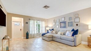 A living room with a sectional sofa, a coffee table, a side table, and a door leading to another room. - -Sea Coast Living At it's BEST, Heated pool, near beaches, shops, restaurants (Naples)