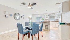 A spacious kitchen with white cabinets, a central island, and a dining area with a glass table and blue chairs. - -Sea Coast Living At it's BEST, Heated pool, near beaches, shops, restaurants (Naples)