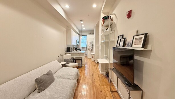 A compact living space with a sofa, a TV, and a kitchenette. - Charming Hoboken location. Fast Path, Bus or Ferry to NYC.  High End Furniture.  (Hoboken)