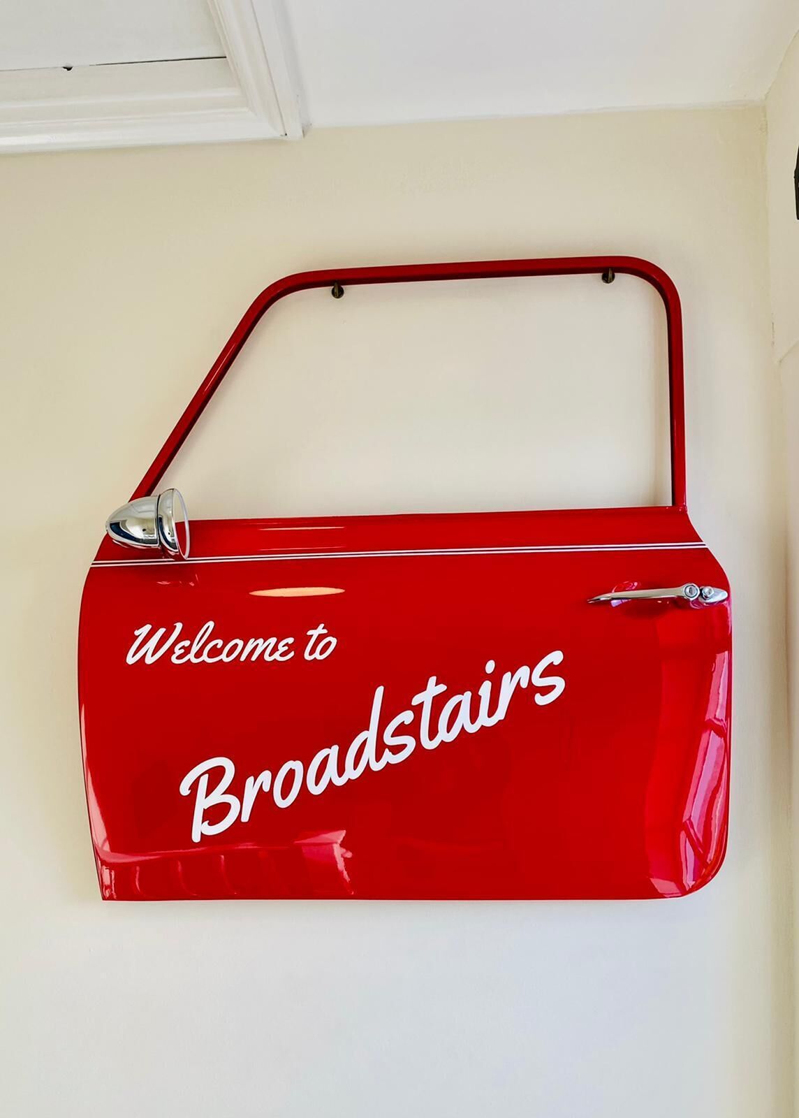 A red, glossy, wall-mounted sign with the text 'Welcome to Broadstairs.'