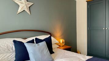 Un llit ben fet amb una decoració d'estreles, una làmpada de nit i un armari en una habitació de disseny senzill i net.