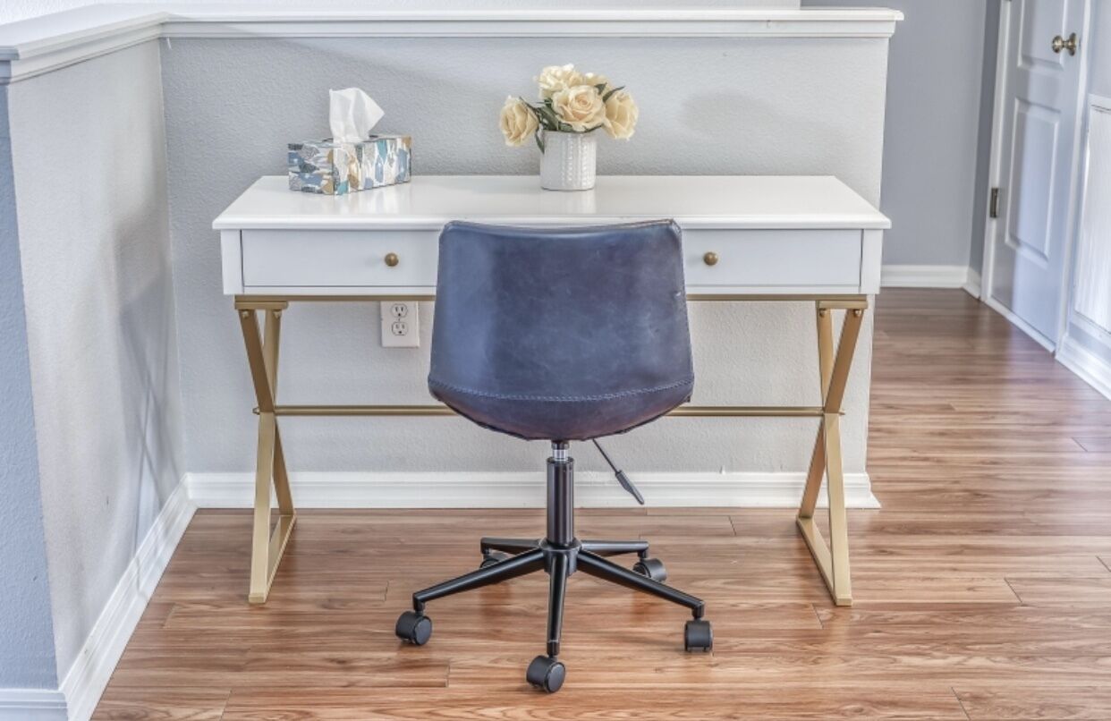 A white desk with a dark blue office chair in front.