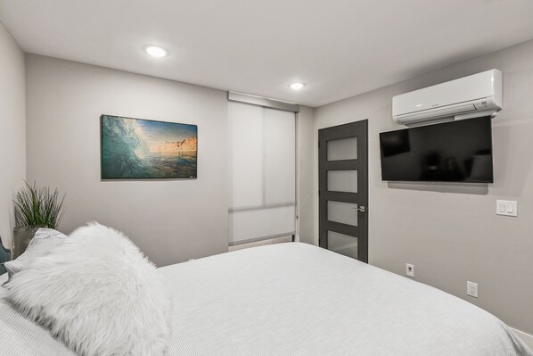 Una camera da letto con un letto, un quadro, un condizionatore d'aria e una televisione.