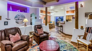Uma sala de estar espaçosa com sofás de couro, uma mesa de centro de madeira e um tapete colorido.