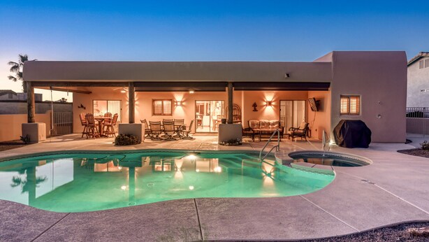 Uma casa moderna com piscina, área de estar externa e um alpendre coberto.