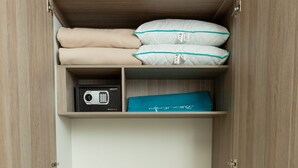 Een houten garderobe met planken en een kledingroede, met opgevouwen dekens en een magnetron.