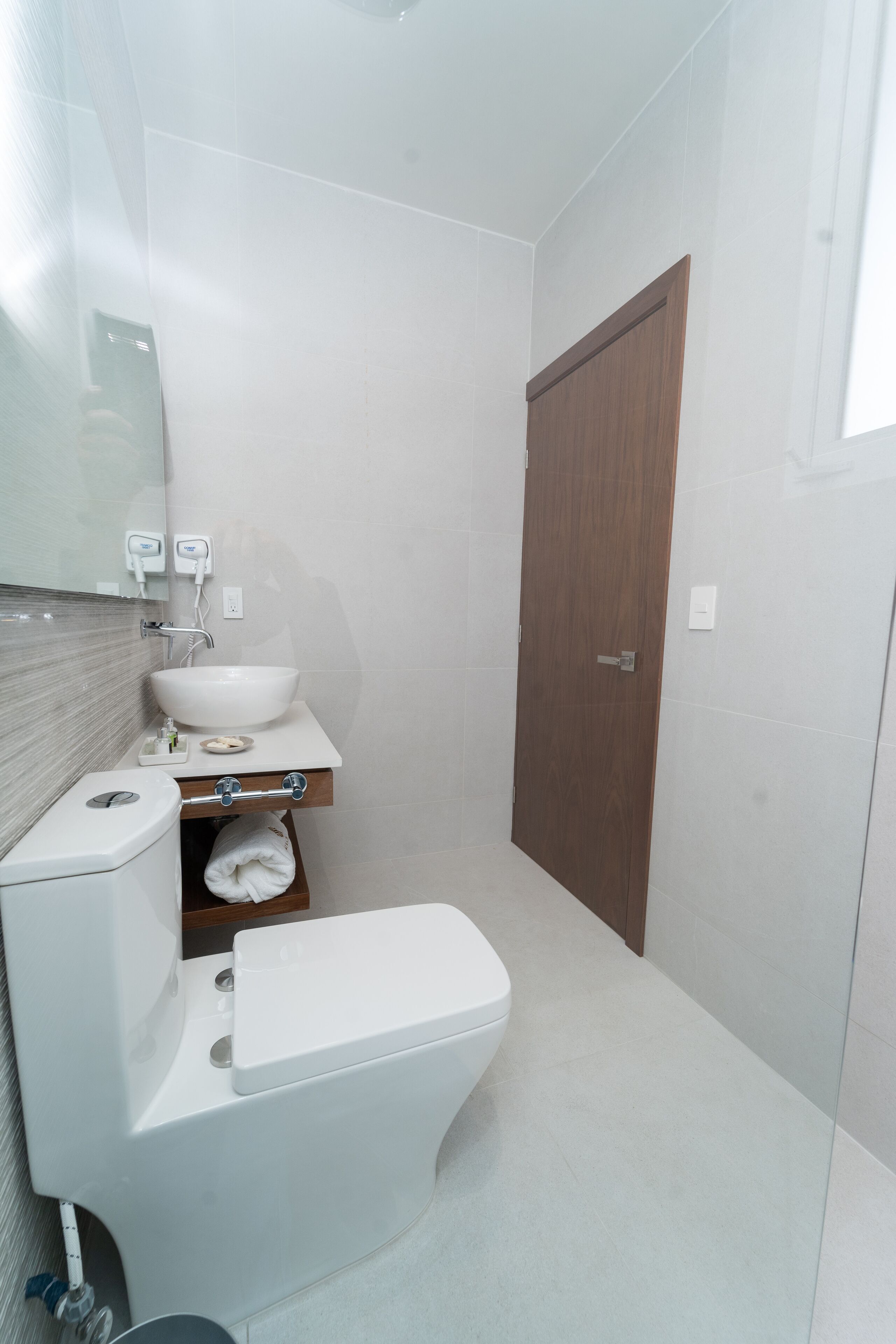 A compact bathroom with a white sink, mirror, and toilet.