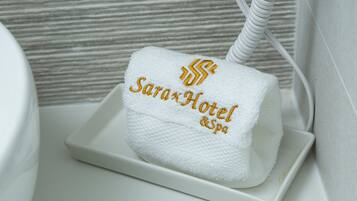 A white towel with embroidered text on a white tray in a bathroom.