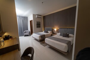 Una habitación de hotel con dos camas, un escritorio, una silla y un baño.