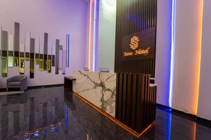 Un mostrador de recepción moderno con encimera de mármol y el logotipo de "Sana Hotel".