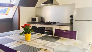 A compact kitchen with a gas stove, microwave, and a clock on the wall. - Agréable Appartement sur les Hauteurs de Quimperlé (Quimperlé)