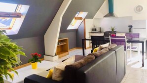 A modern loft apartment with a dining area, kitchen, and a large window. - Agréable Appartement sur les Hauteurs de Quimperlé (Quimperlé)