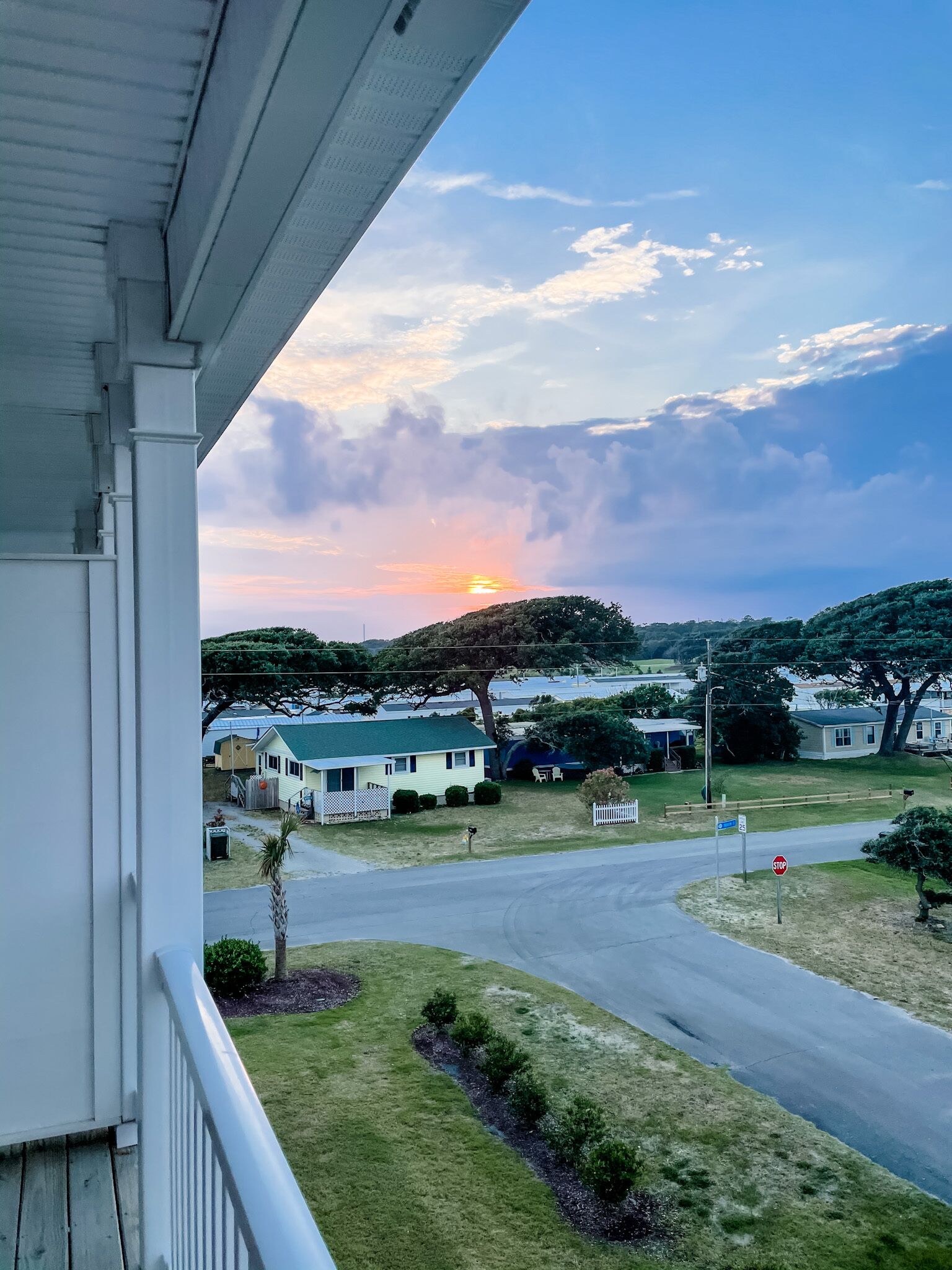 Un quartier résidentiel avec des maisons, un panneau de signalisation et un ciel dégagé avec quelques nuages.