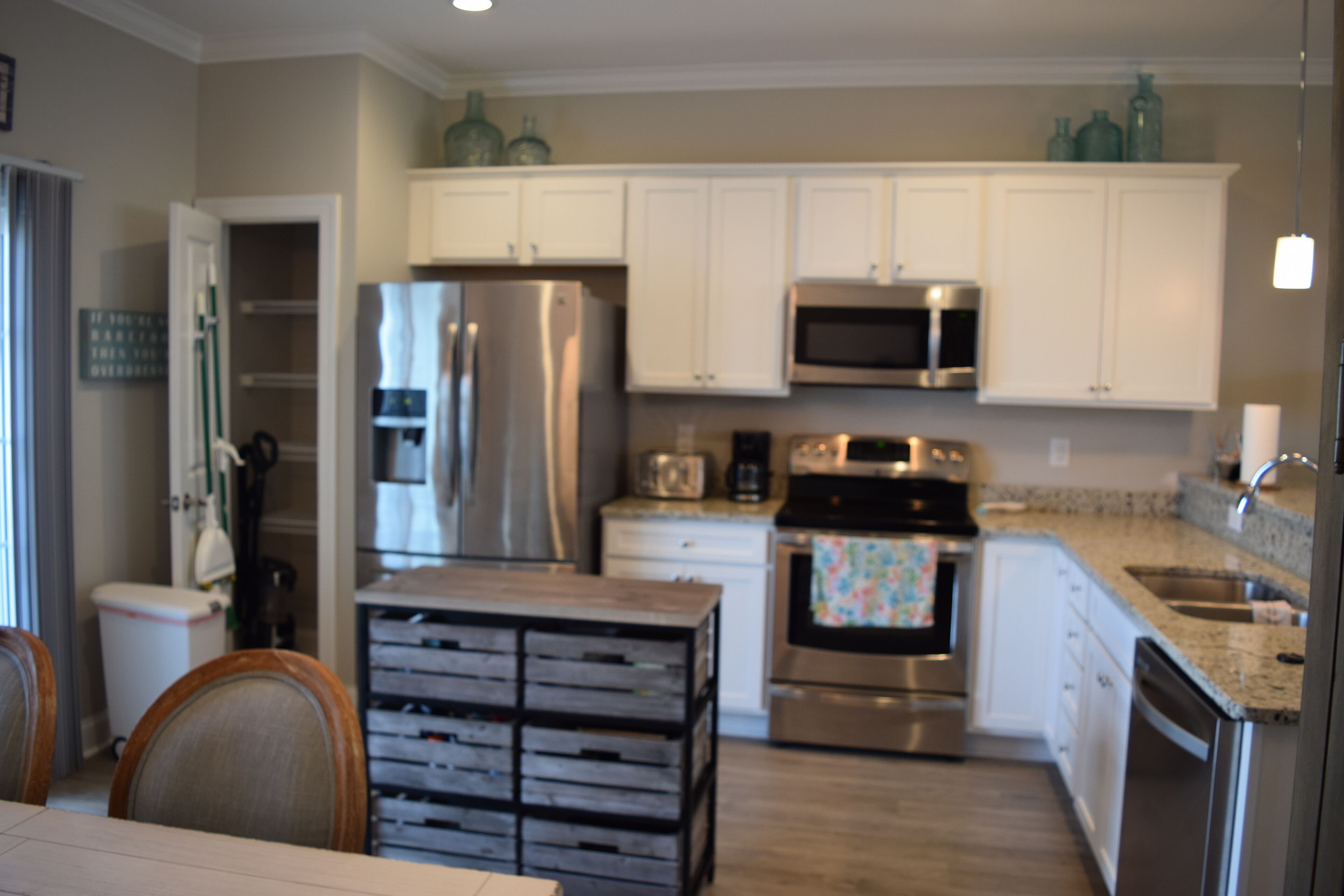 A modern kitchen with white cabinets, stainless steel appliances, and a granite countertop.
