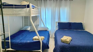 A room with bunk beds, a ceiling fan, and a window with curtains. - Cozy 5 Bedroom 85” TV Home in a Secluded Area (Jacksonville)