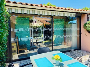 Un patio con una mesa, sillas, una puerta verde y un techo de tejas.