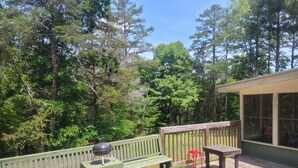 A wooden deck with a grill, a bench, and a table.