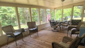 A covered patio with wicker furniture, a table, and chairs.