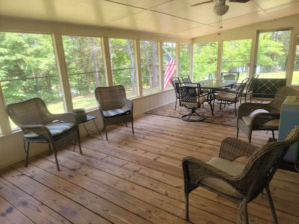 A covered patio with wicker furniture, a table, and chairs.