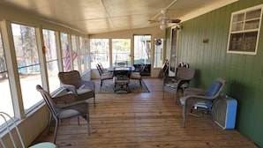 A covered patio area with wicker furniture, a table, and chairs.
