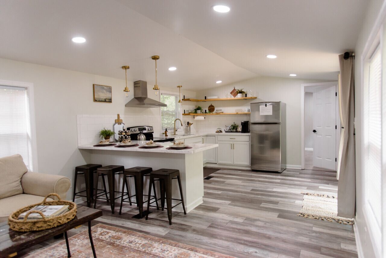 A modern kitchen with a central island, bar stools, and a refrigerator.