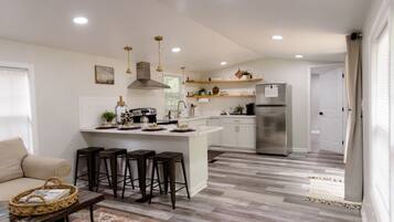 A modern kitchen with a central island, bar stools, and a refrigerator.